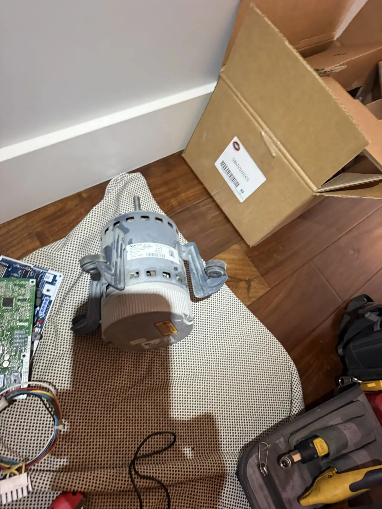 Old furnace blower motor removed next to new replacement motor box in Palo Alto home