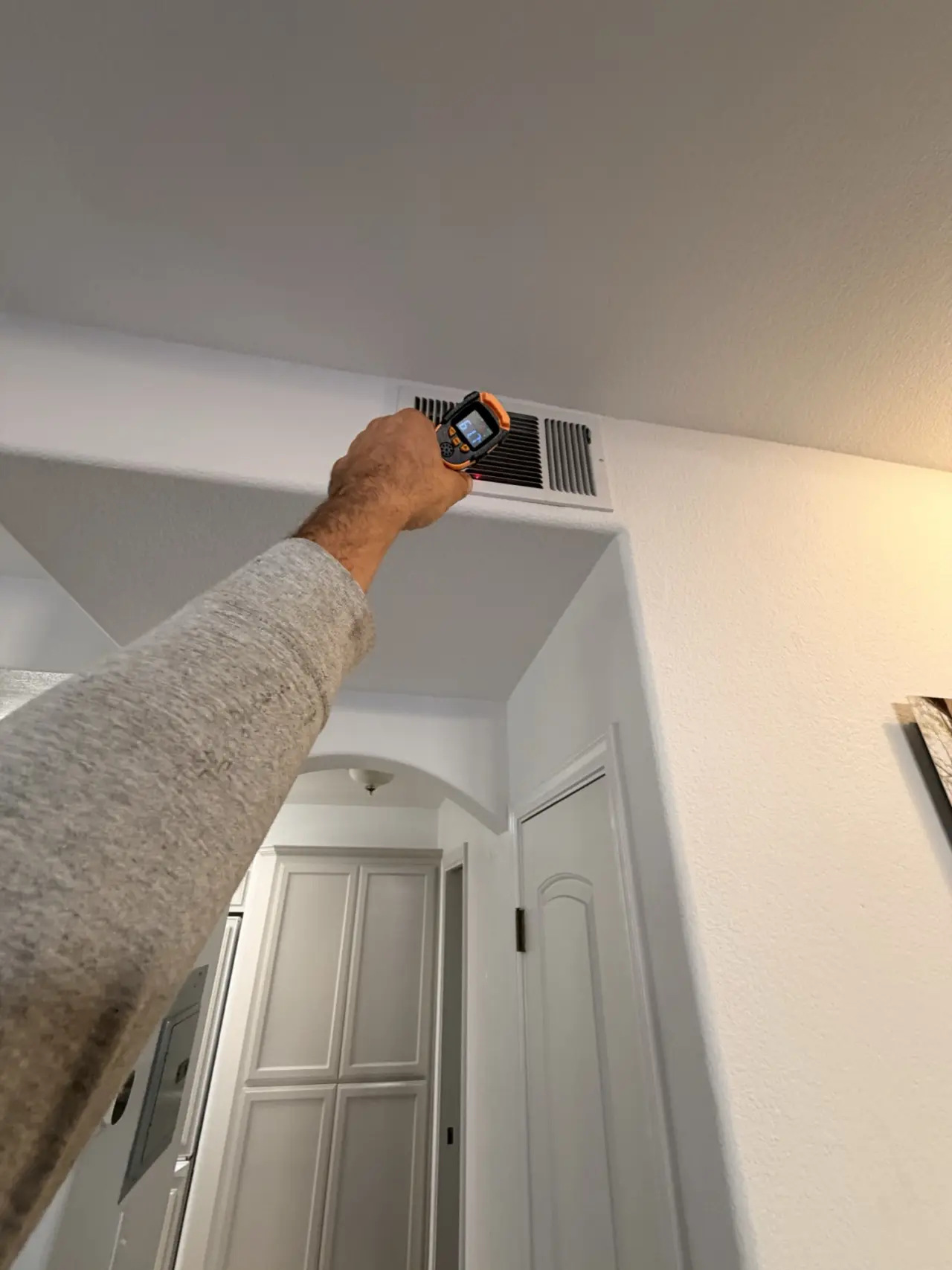 Checking supply air temperature at a ceiling register after a Mountain View heat pump installation