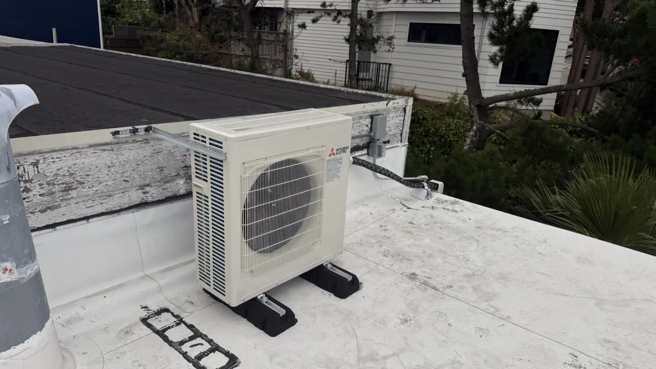 Mitsubishi heat pump condenser secured on a roof mounting rail in San Francisco