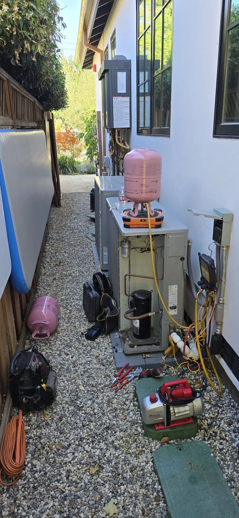Outdoor HVAC condenser with refrigerant recovery tank and vacuum pump during a leak repair in Burlingame