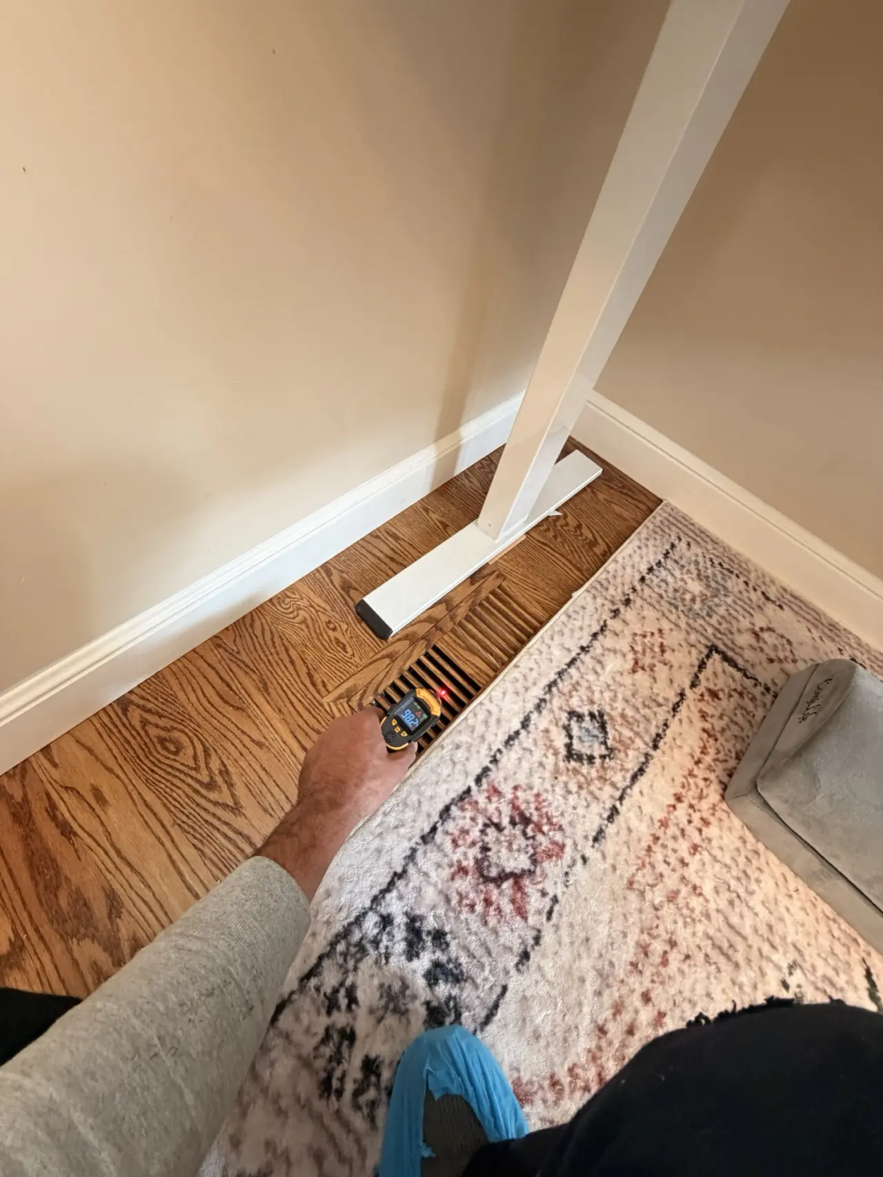Checking airflow at a hardwood floor register after a San Mateo heat pump installation