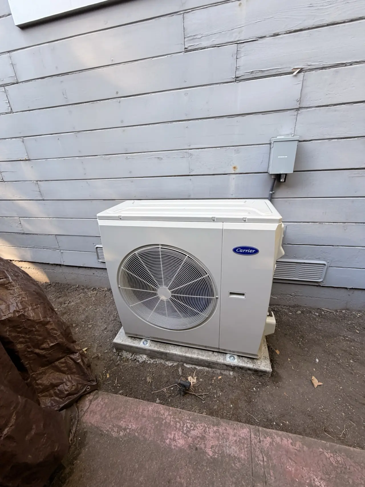Front view of a Carrier heat pump condenser installed in Redwood City