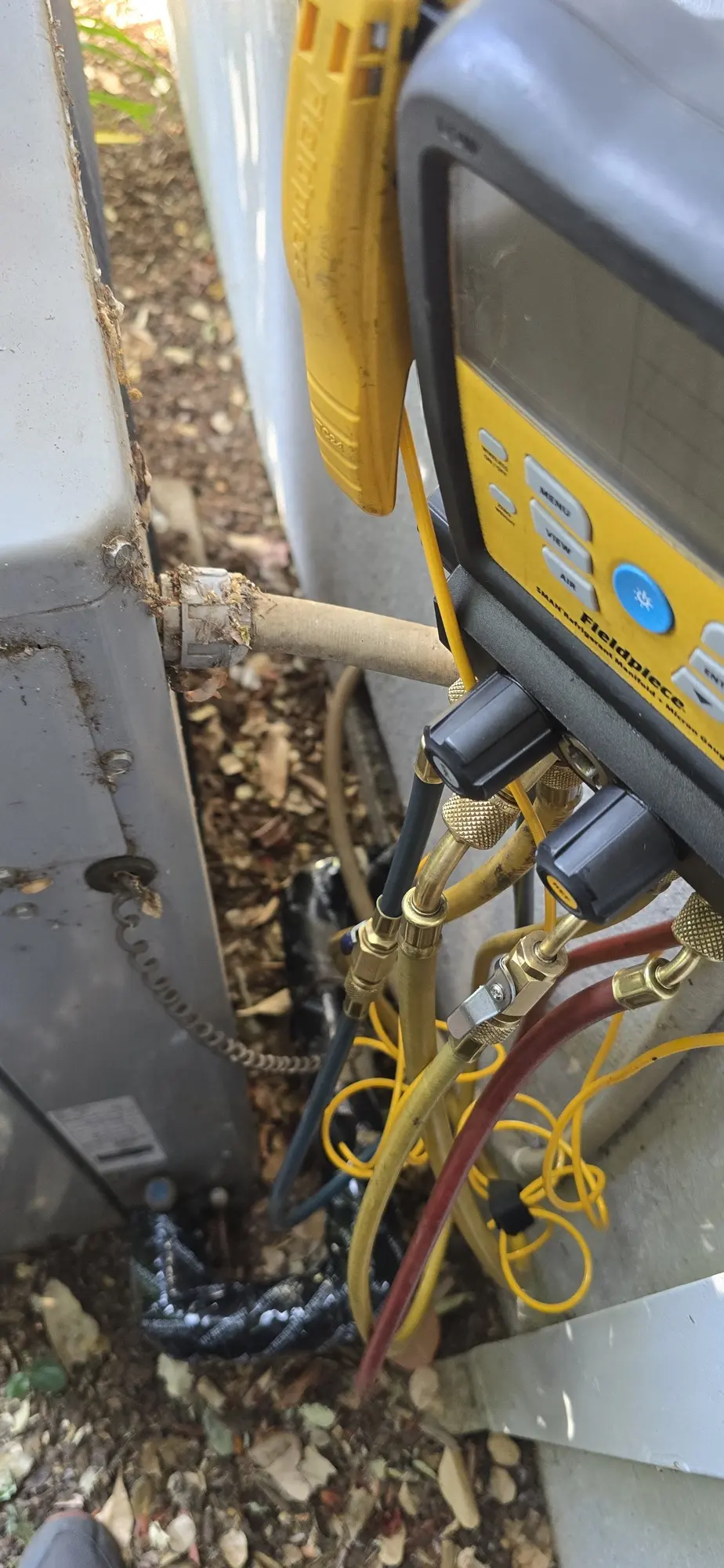 Manifold gauges connected to the suction line service valve of an HVAC condenser in Los Altos