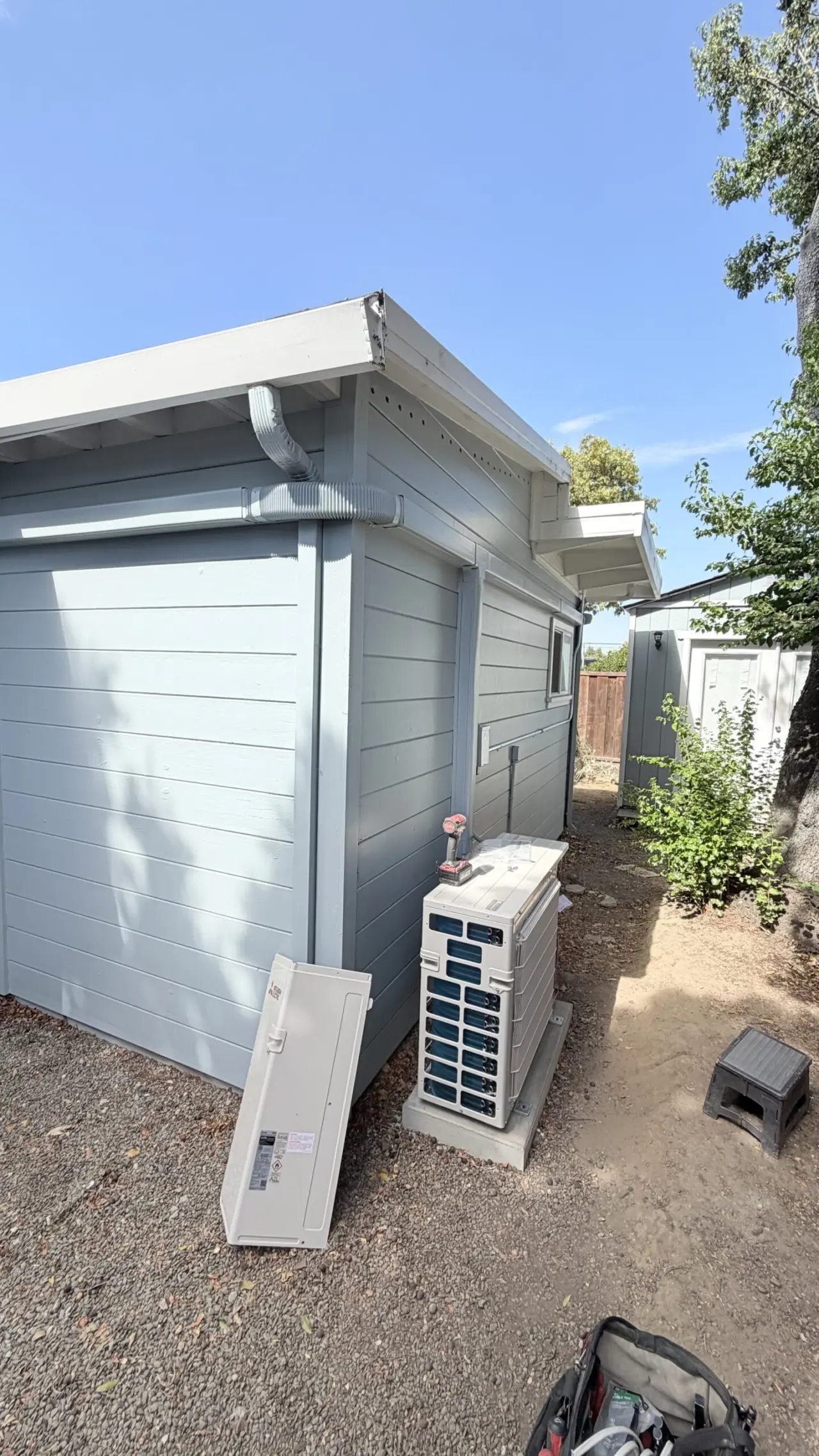 Mitsubishi heat pump condenser unit set beside a San Mateo garage