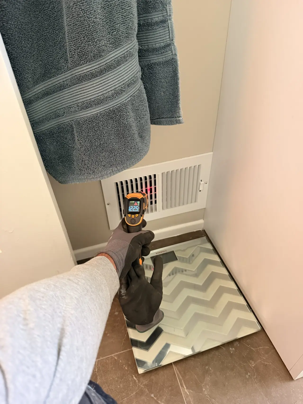 Technician checking supply air temperature at a vent after furnace installation in San Bruno