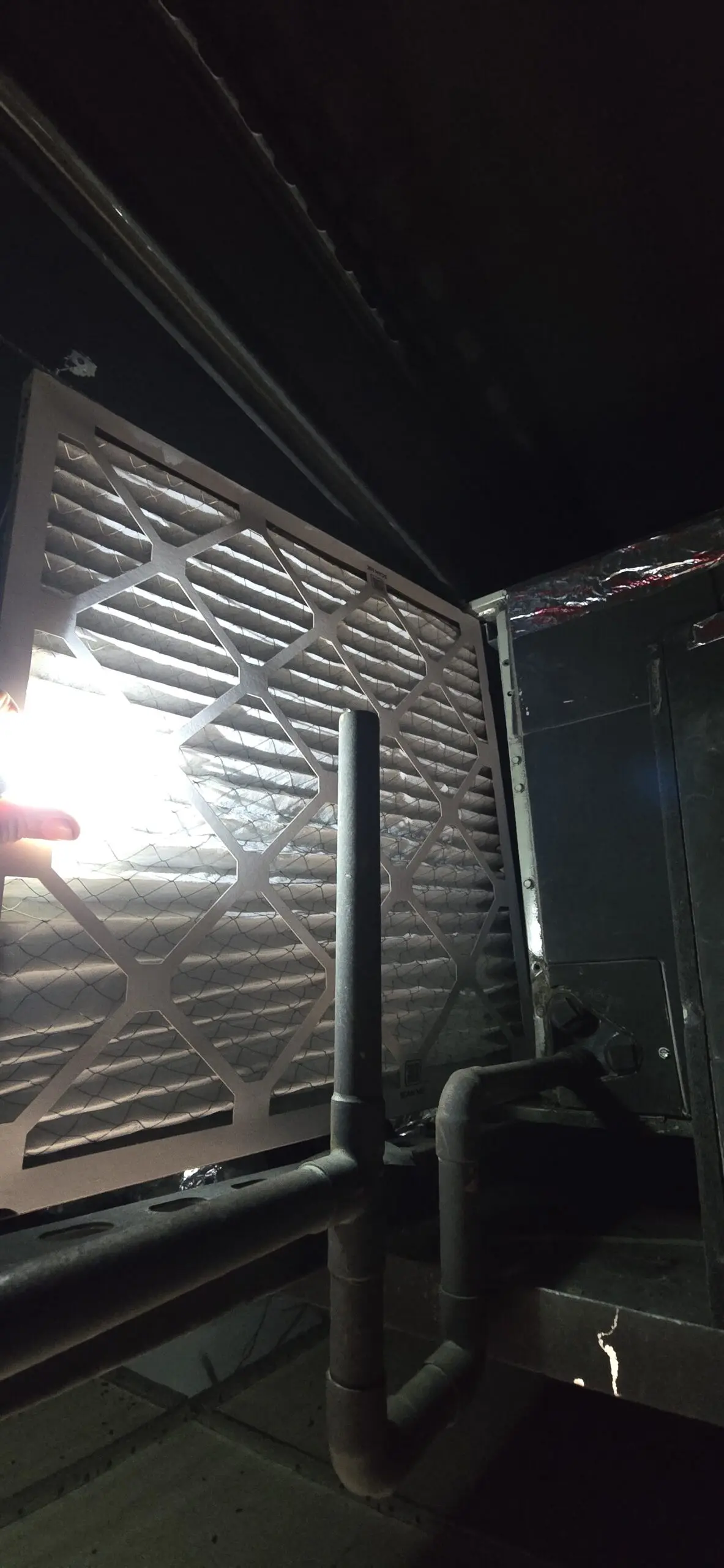 New pleated filter held up during above-ceiling filter installation in Millbrae