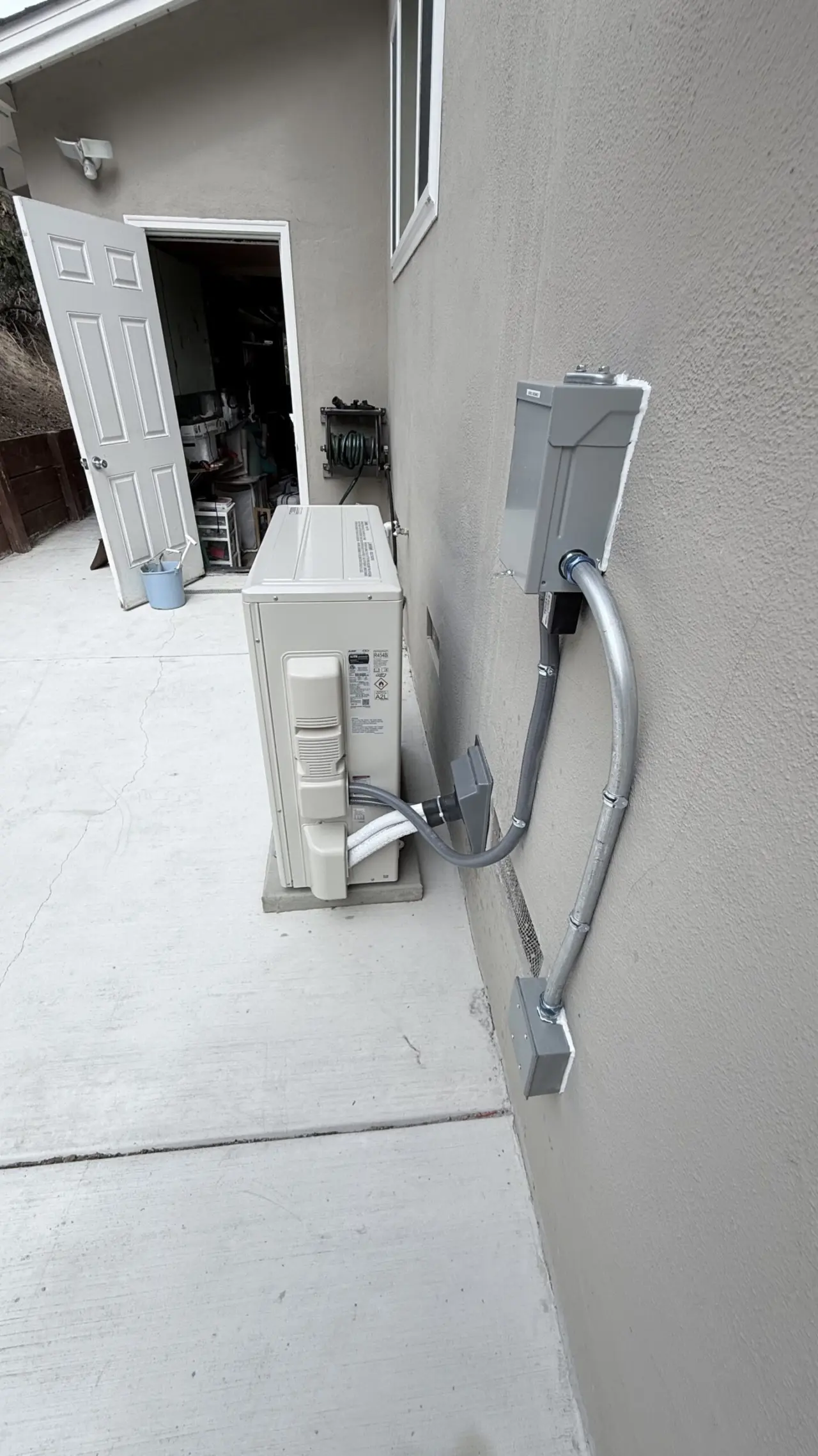 Mitsubishi heat pump outdoor unit with line set cover and service disconnect in San Mateo