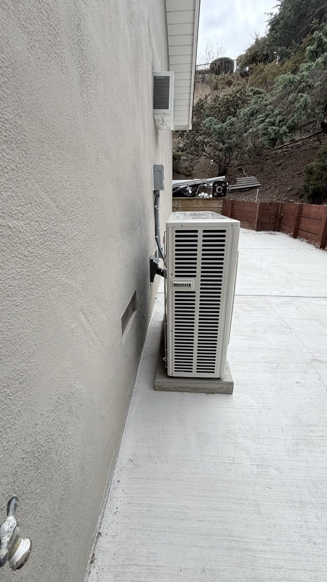 Side view of a Mitsubishi heat pump condenser installed along a house in San Mateo