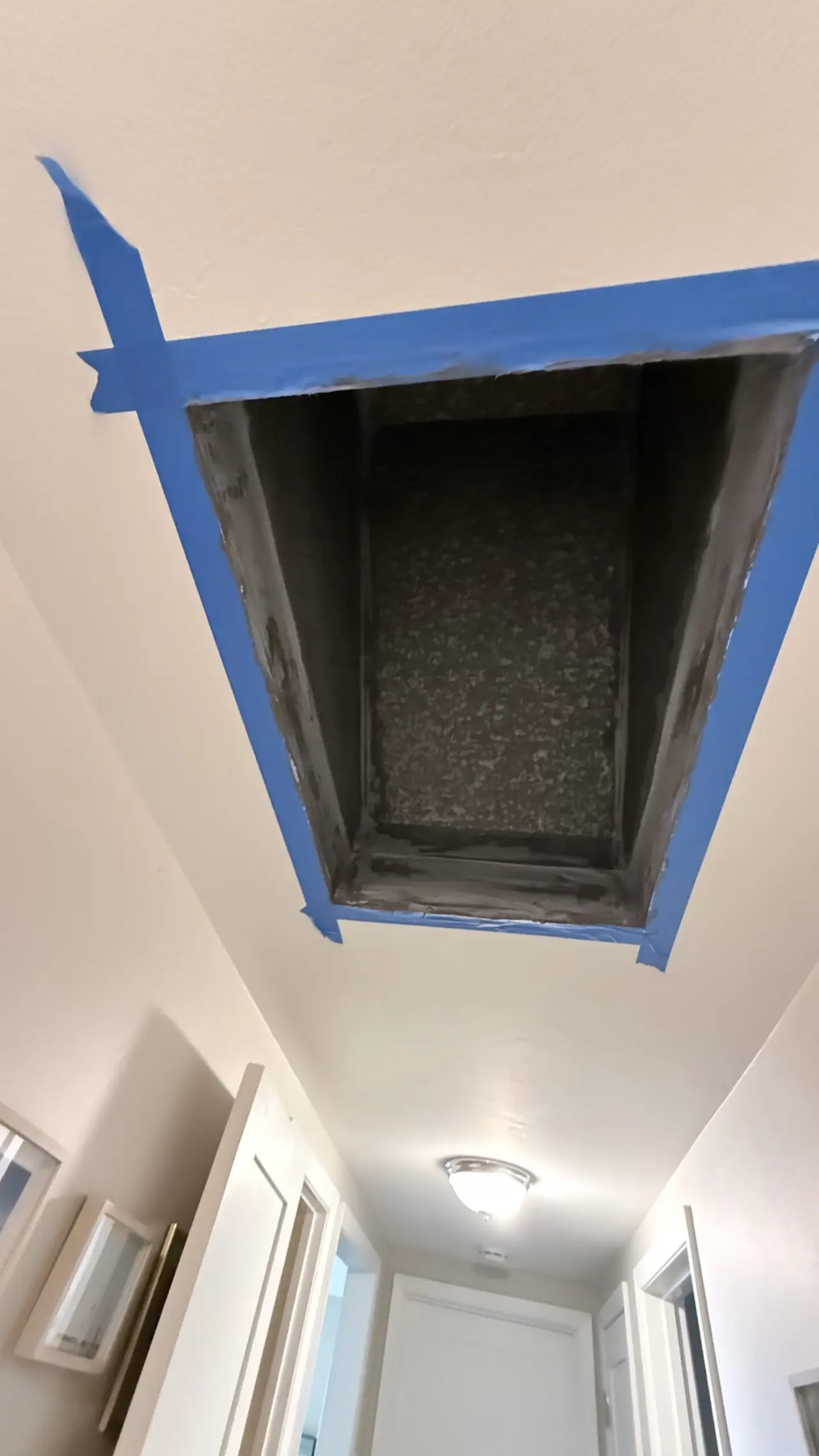 Hallway ceiling return air opening taped off during heat pump ductwork work in San Mateo
