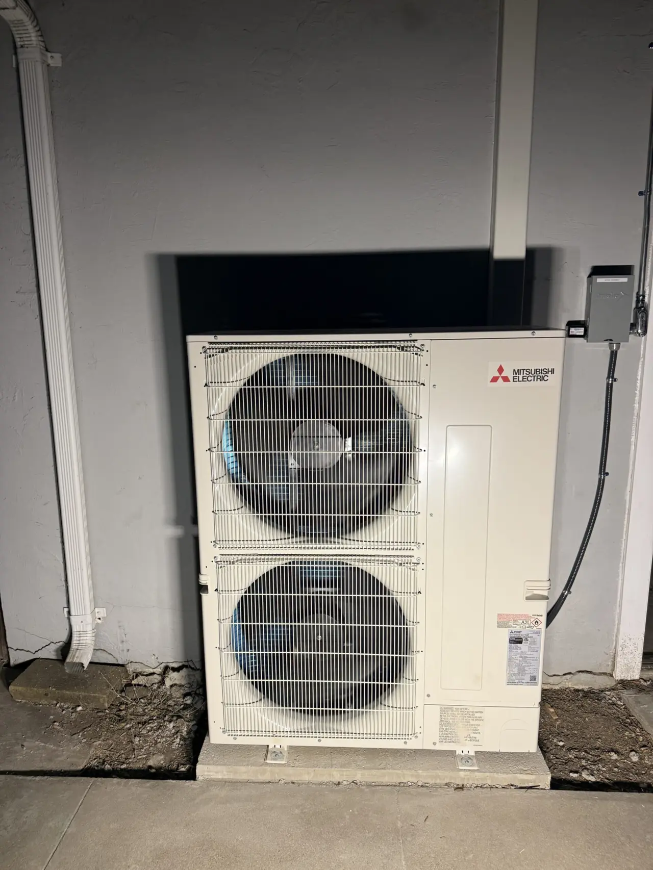 Mitsubishi Electric 3-ton heat pump outdoor unit on a concrete pad beside a house in Santa Clara, with wall-mounted disconnect