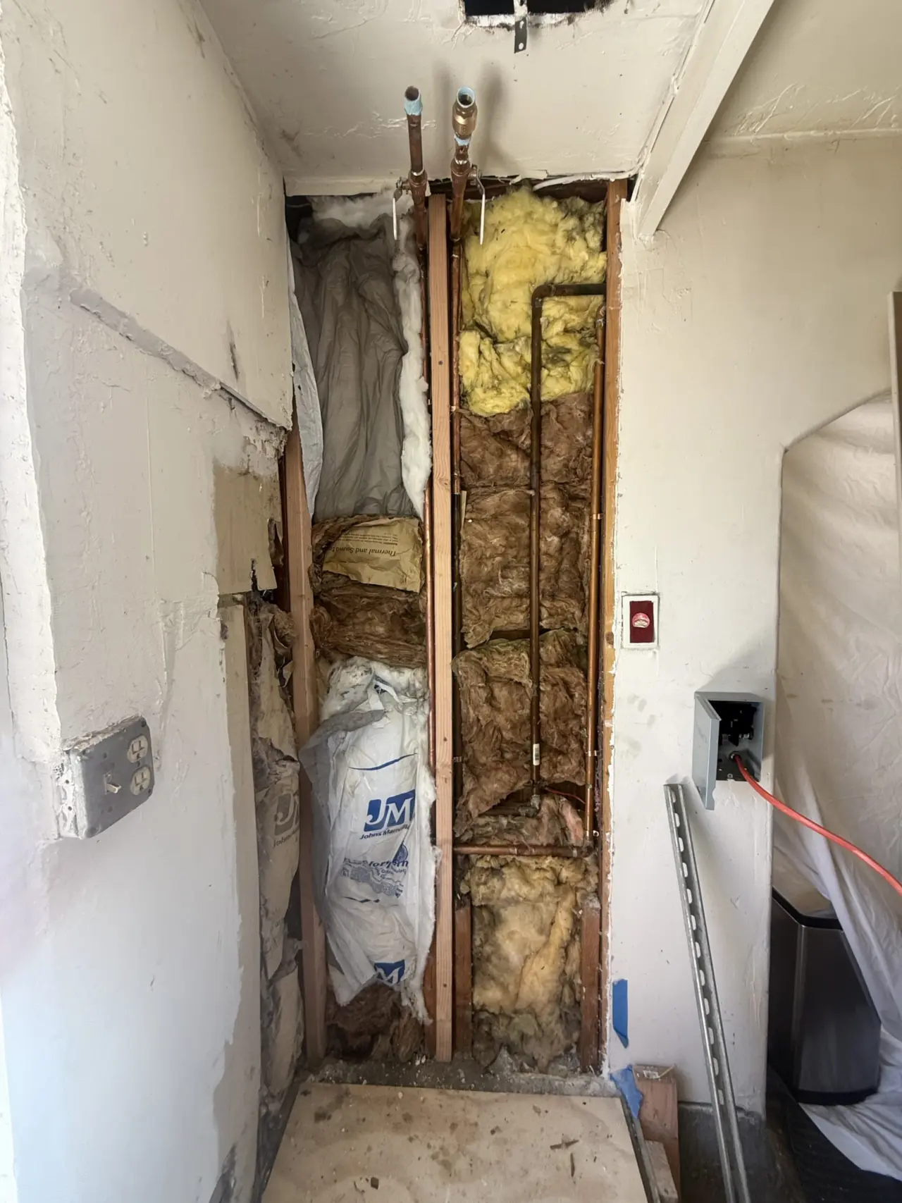 Wall cavity re-insulated around copper plumbing before closing it up for a heat pump water heater in South San Francisco